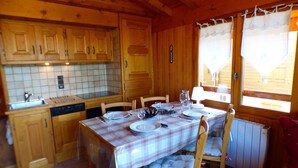 A wooden cabin with a kitchen featuring wooden cabinets, a tiled backsplash, and a dining table set for four. - 2-room apartment Les Saisies, top of resort, 6 people, balcony. (Les Saisies)