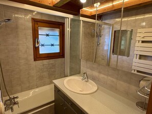 Un baño con bañera, lavamanos, ducha y espejo.