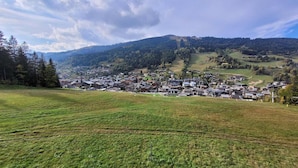 A rural village with traditional houses, a clear sky, and surrounding hills.
