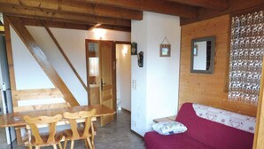 Un intérieur en bois comprenant une table à manger, des chaises, un canapé rouge et un mur orné de motifs.