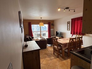 A compact living space with a dining area, a TV, and a view of a mountainous landscape.