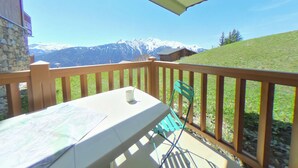 Un balcon avec une table et des chaises, donnant sur un paysage montagneux.