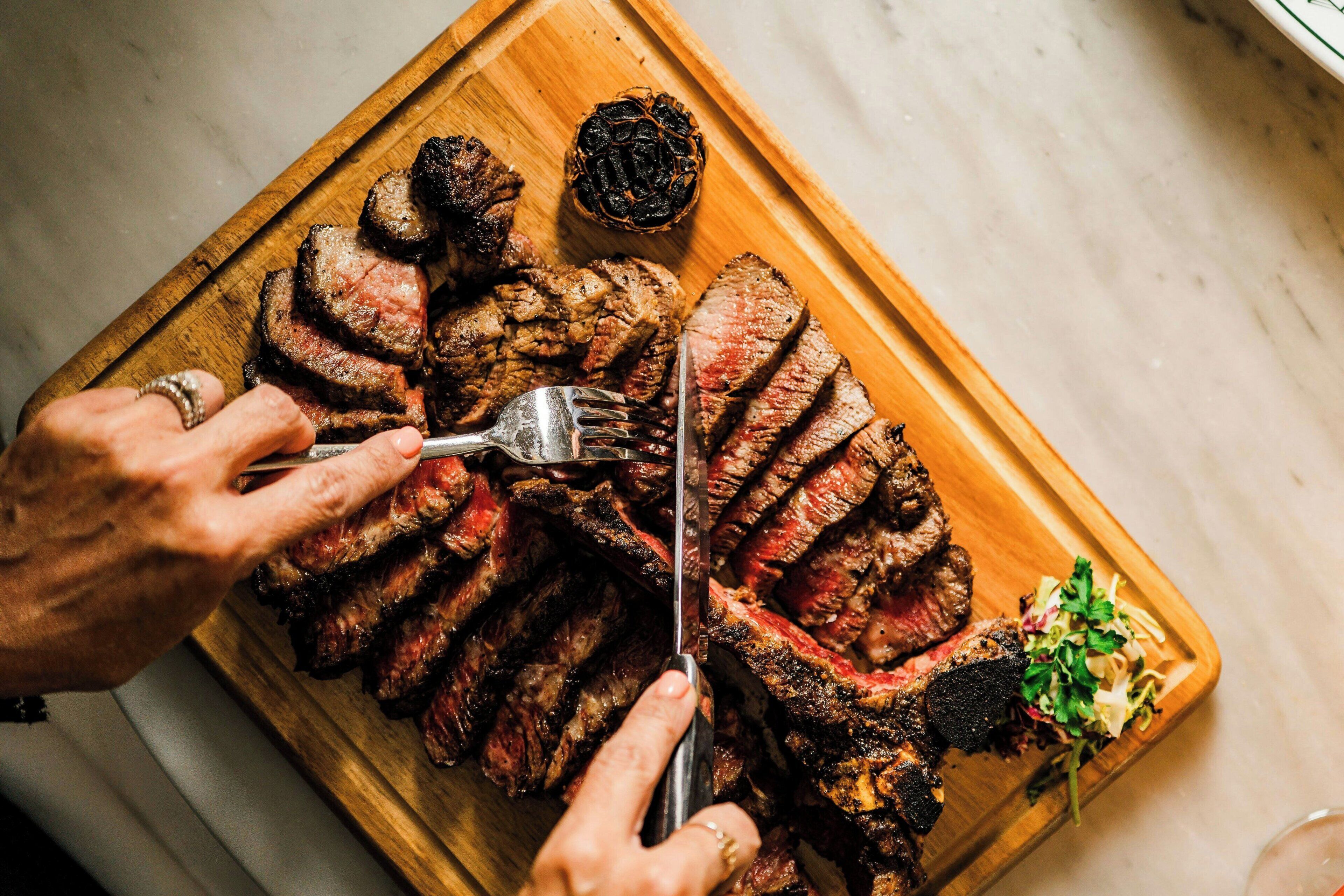 Une planche à découper en bois avec des tranches de viande et une fourchette.