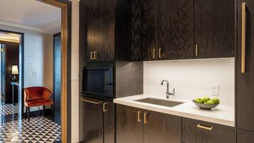 A modern kitchen with dark wood cabinets, a white countertop, and a black microwave.