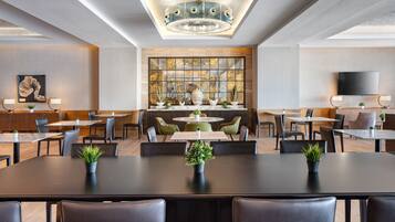 Un espace repas moderne avec des tables rondes, des chaises noires et des plantes en pot.