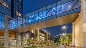 Un bâtiment moderne doté d’un pont de verre et d’une enseigne lumineuse.