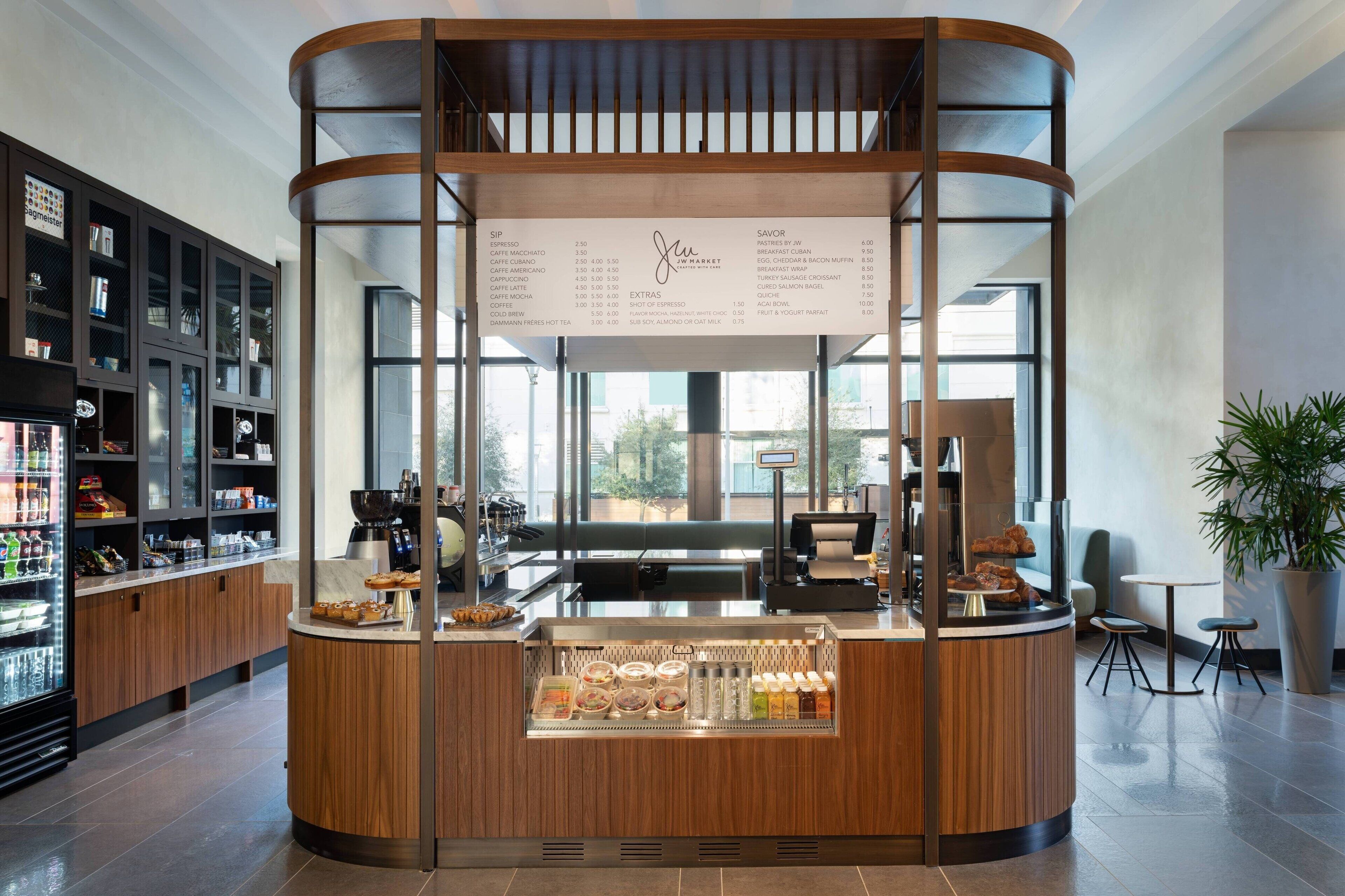Un café moderne avec un comptoir en bois, un tableau affichant le menu et une vitrine réfrigérée.