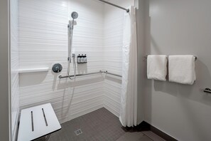 A modern bathroom with a shower, a hand dryer, and a towel rack.