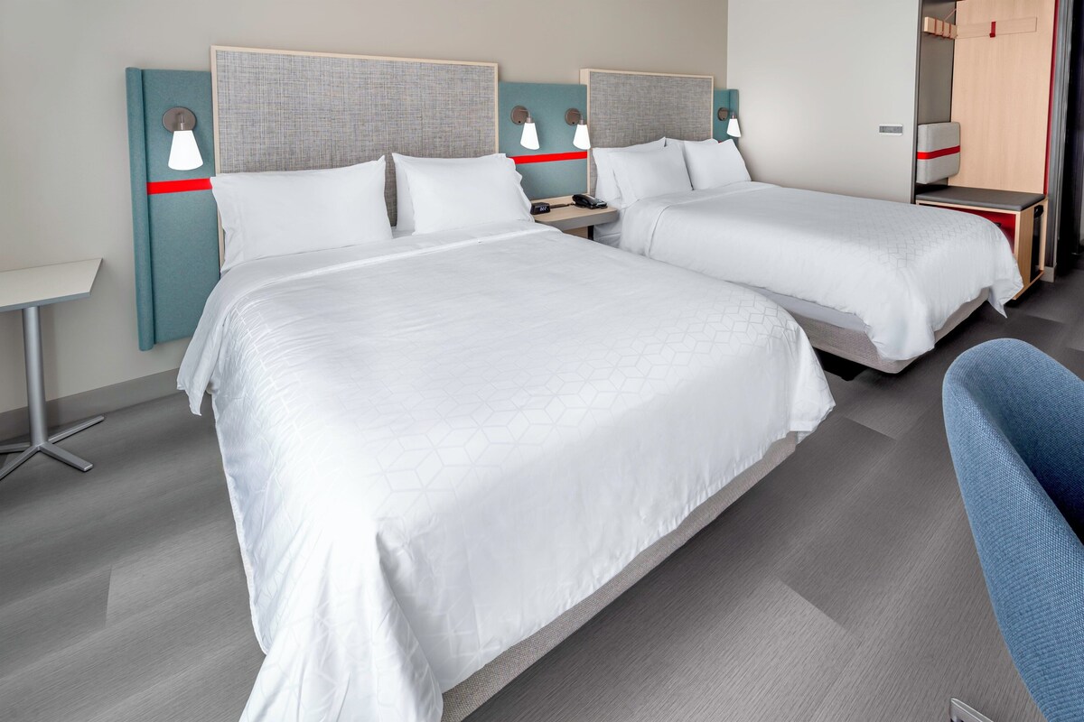 Ein Hotelzimmer mit zwei Betten, einem Schreibtisch und einem Stuhl.