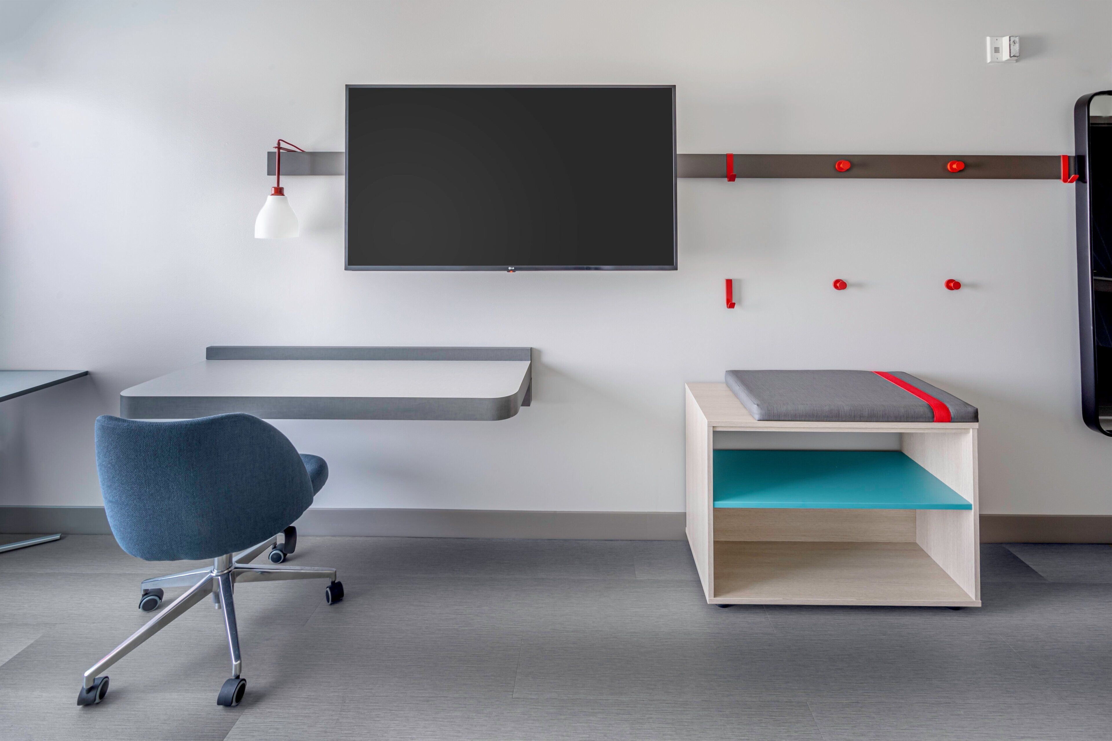 A modern office space with a desk, chair, and a mounted TV.