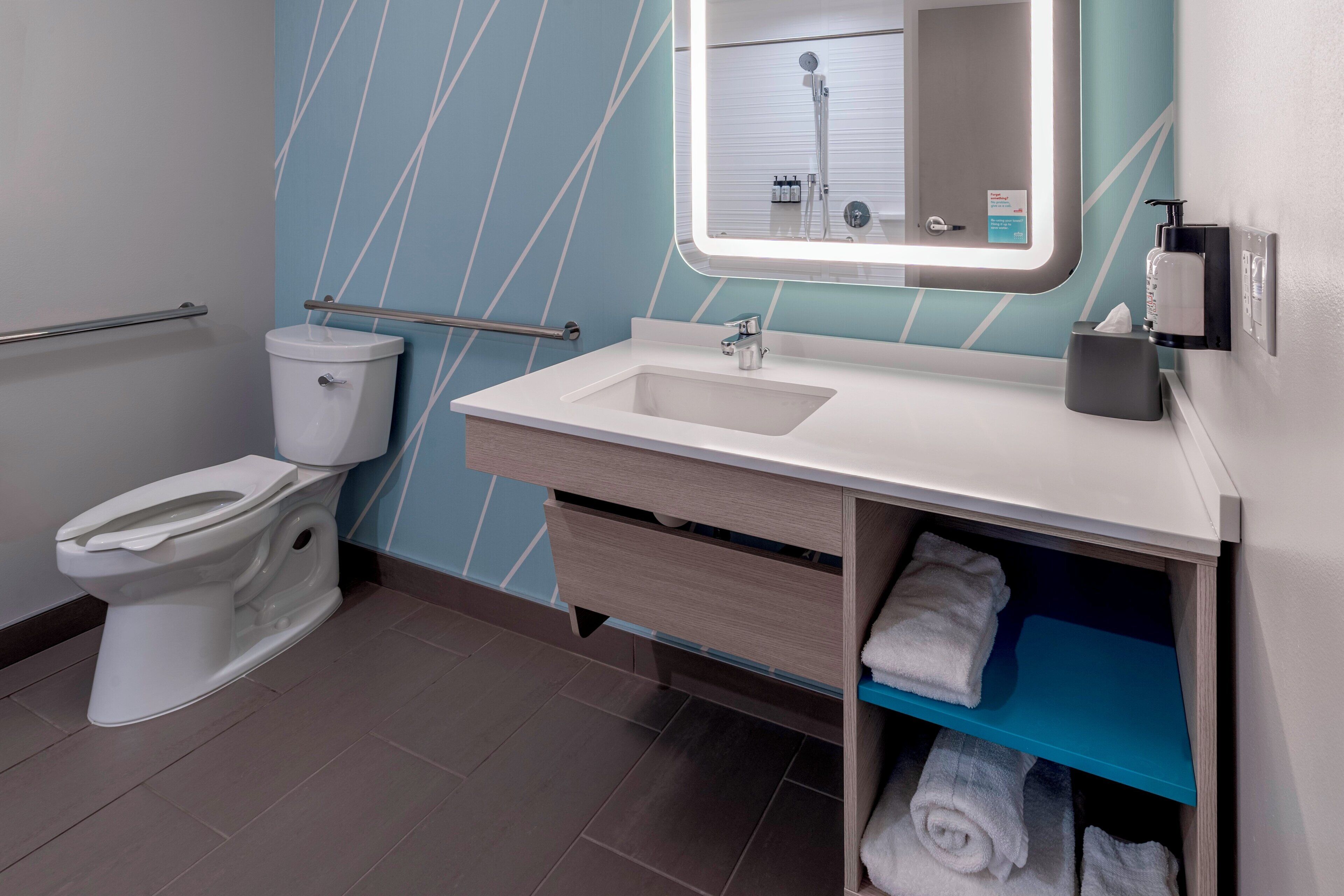 A modern bathroom with a toilet, sink, and towel storage.