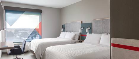 A hotel room with two beds, a desk, and a chair.