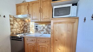 A compact kitchen with wooden cabinets, a microwave, and a dishwasher.