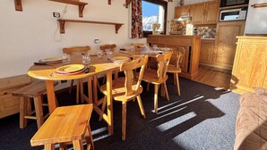 A cozy kitchen with wooden cabinets, a dining table set for four, and a view of the mountains through the window.