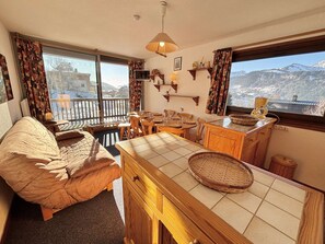 Una habitación acogedora con una cama, una mesa de comedor y una zona de cocina con vistas a las montañas.