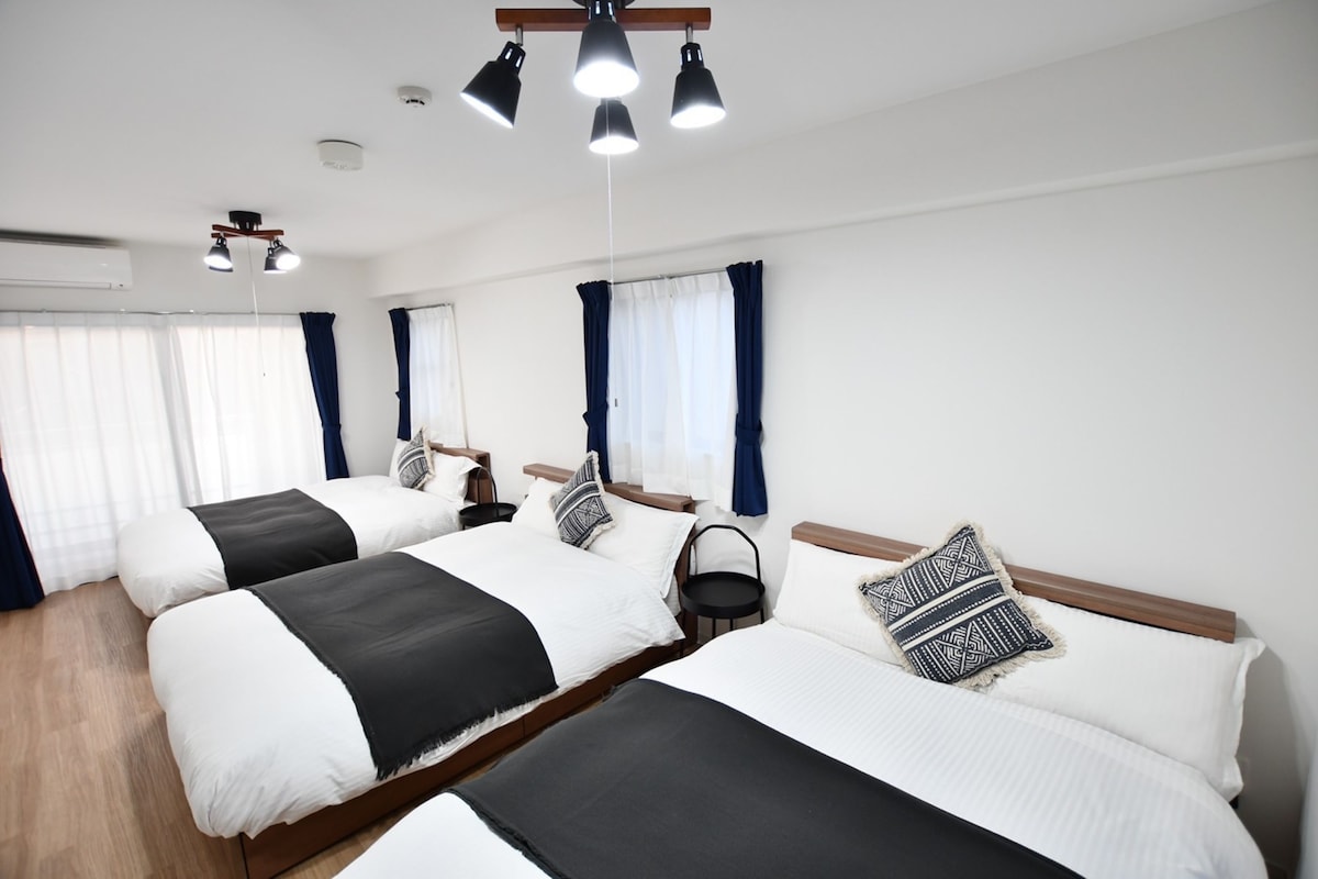 Une chambre d’hôtel avec deux lits, un ventilateur de plafond et une petite table.