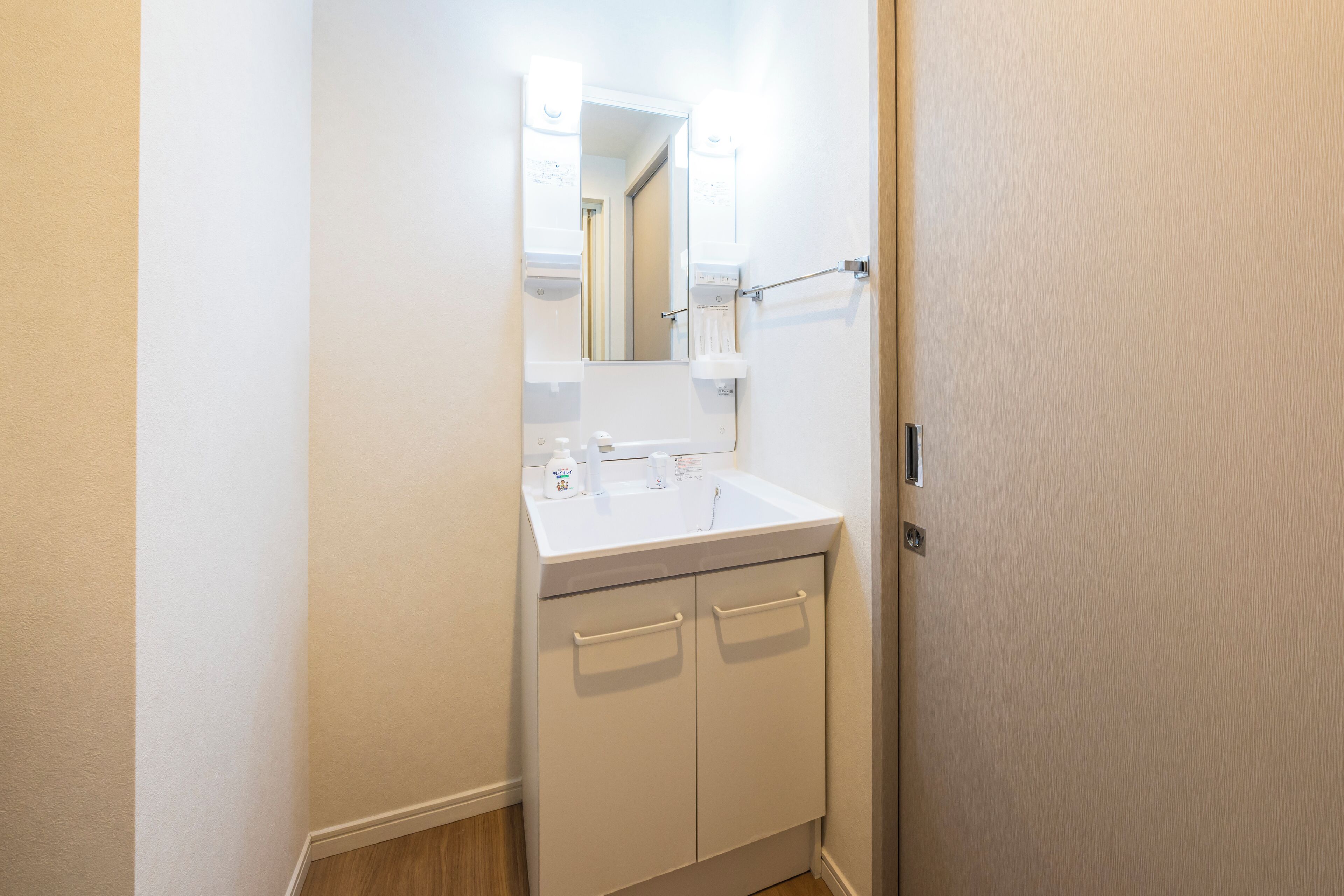 Een badkamer met een witte wastafel, spiegel en kast.