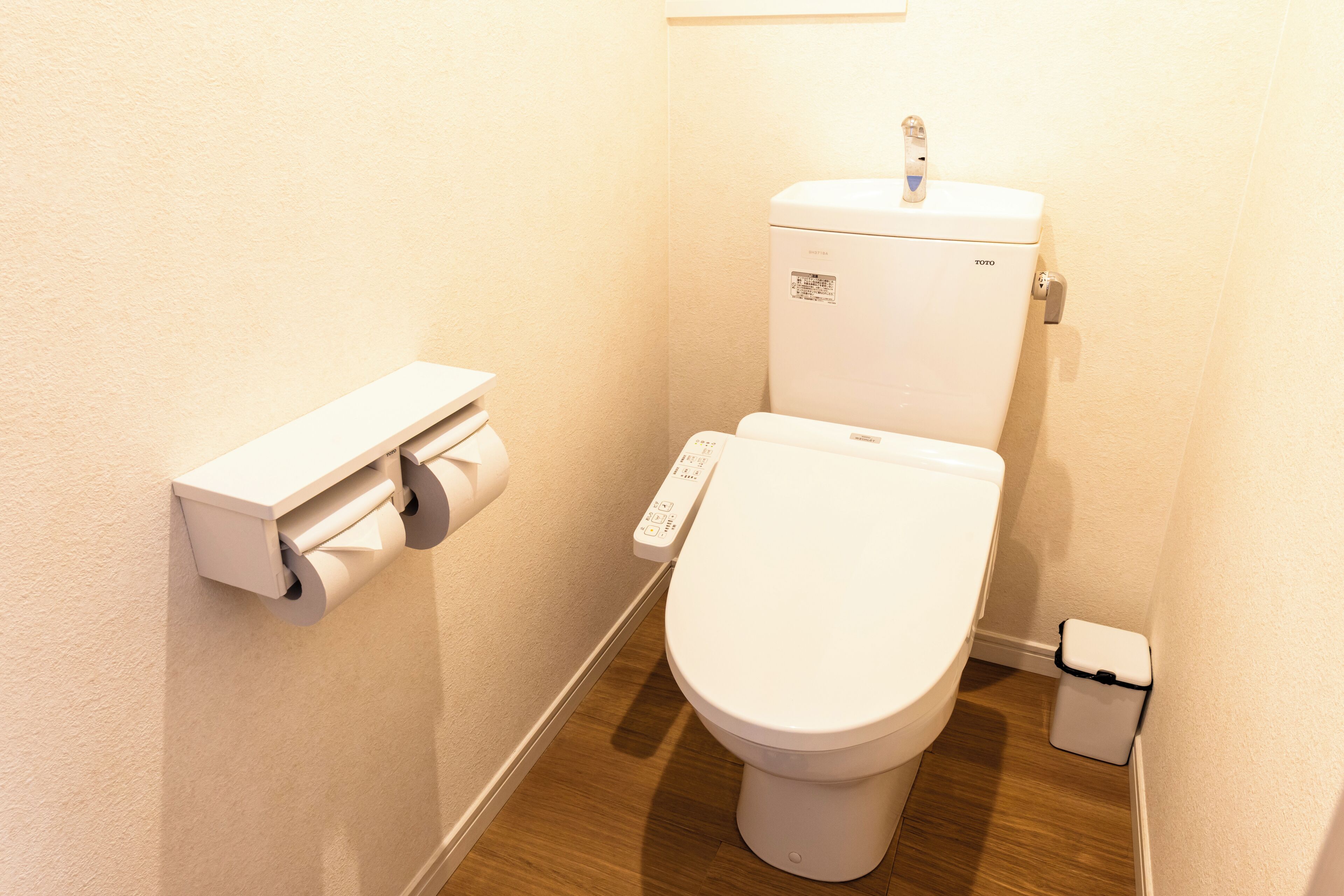 Ein kleines, sauberes Badezimmer mit Toilette, Papierhandtuchspender und Mülleimer.