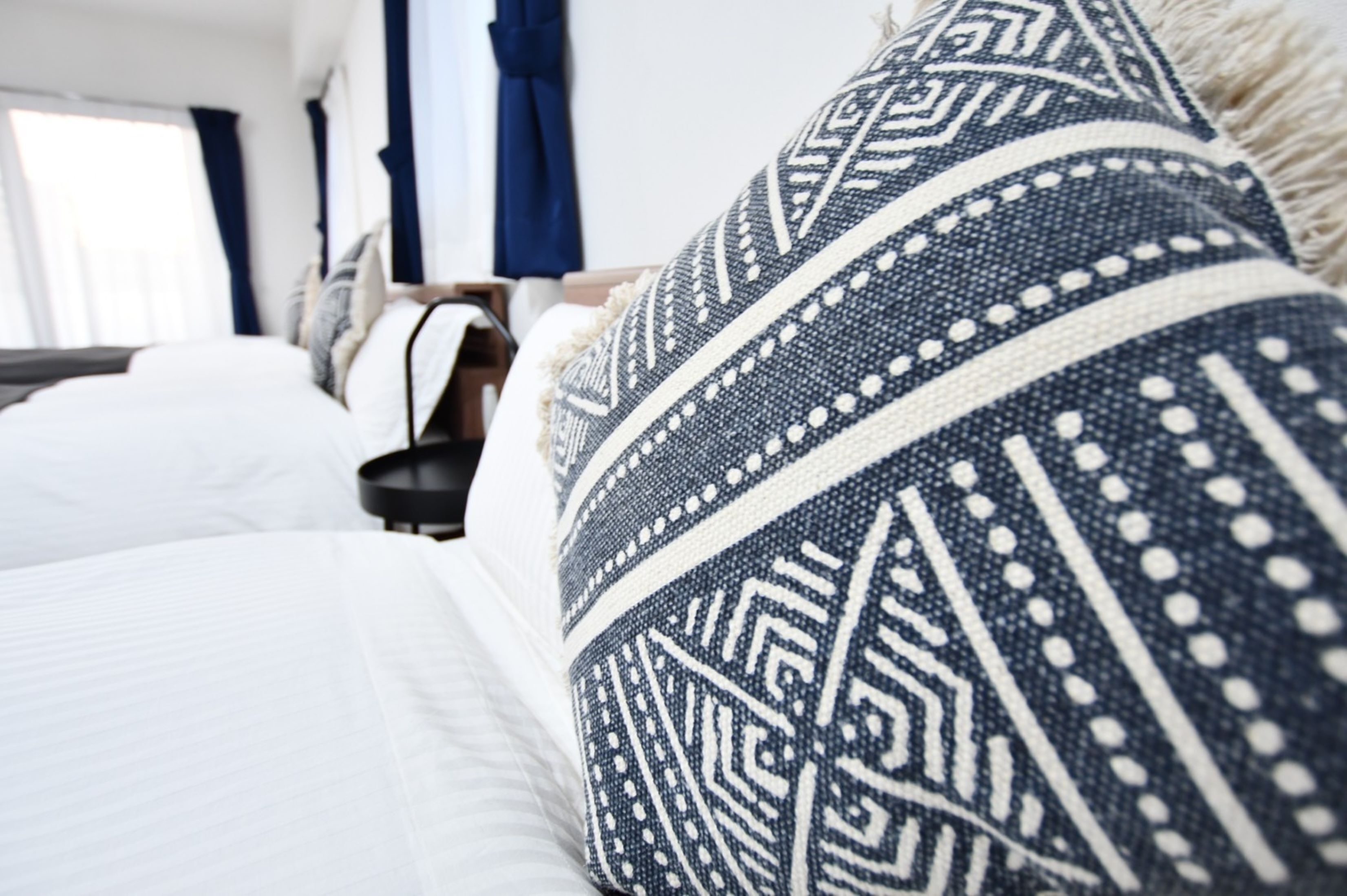 A bed with white bedding and a blue and white patterned pillow.
