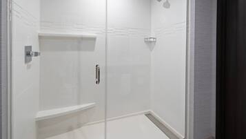 A modern shower with a glass door, a built-in bench, and a wall-mounted showerhead.