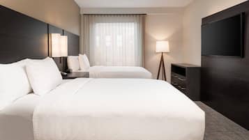 Ein Hotelzimmer mit einem großen Bett, zwei Nachttischen, einem Fernseher und einem Fenster mit Vorhängen.