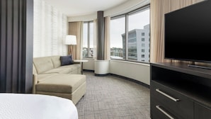 A hotel room with a large bed, a sofa, a TV, a small table, and a window offering a city view. - Residence Inn by Marriott Grand Rapids Downtown (Grand Rapids)