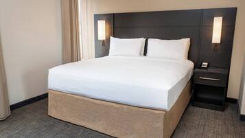 Habitación de hotel con una cama grande, una mesita de noche con un teléfono y una lámpara fijada a la pared.