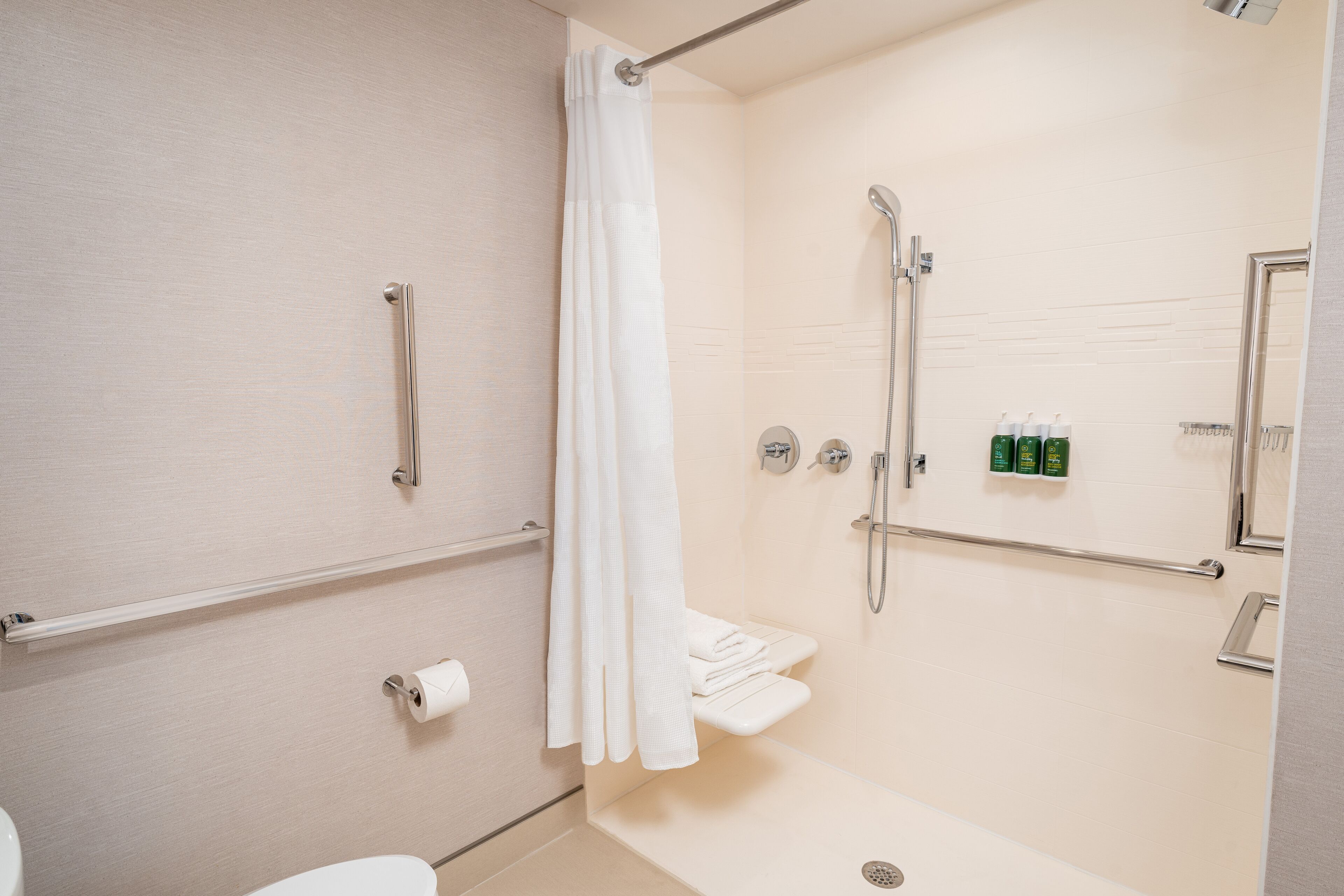 Un baño moderno con ducha, inodoro y barras de apoyo.
