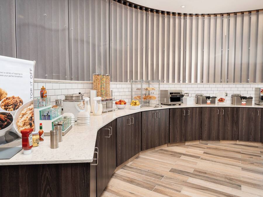 Una cocina moderna con una encimera curva, diversos alimentos y un panel vertical grande en la pared.