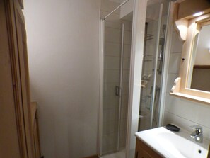 A bathroom with a glass-enclosed shower, a white sink, and a mirror above it. - 5-room apartment for 8 ppl in Les Saisies (Les Saisies)