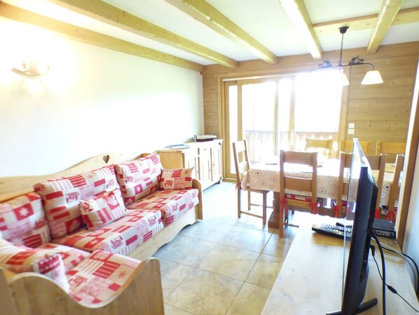 A cozy living room with a wooden sofa, a dining table with chairs, and a television. - 5-room apartment for 8 ppl in Les Saisies (Les Saisies)