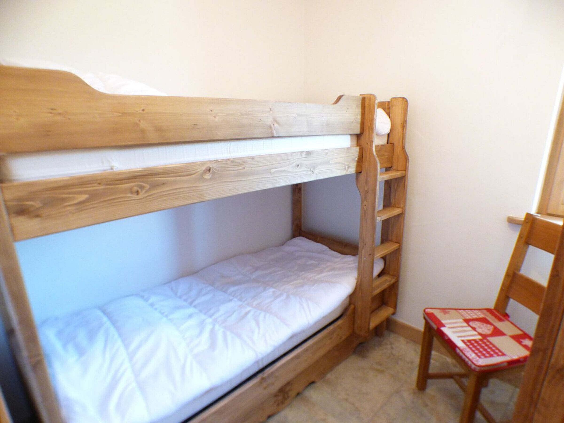 A bunk bed with a wooden frame and white bedding.