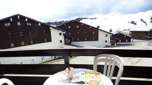 A balcony with a table, chairs, and a view of snow-covered buildings and mountains. - Studio cabin 4 pers, balcony, in Les Saisies (Les Saisies)