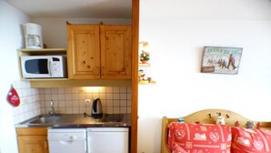 A compact kitchen with wooden cabinets, a microwave, a kettle, and a small sink. - Studio cabin 4 pers, balcony, in Les Saisies (Les Saisies)