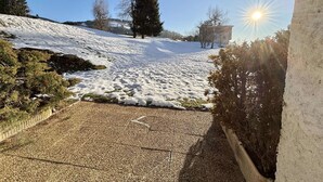 A snowy outdoor area with a paved path leading uphill, surrounded by trees and a building in the background. - Studio at the foot of the slopes in Notre-Dame-de-Bellecombe (Notre-Dame-de-Bellecombe)