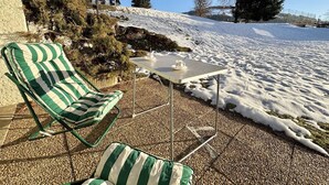 A patio with a striped lounge chair and a small table with a cup and saucer. - Studio at the foot of the slopes in Notre-Dame-de-Bellecombe (Notre-Dame-de-Bellecombe)