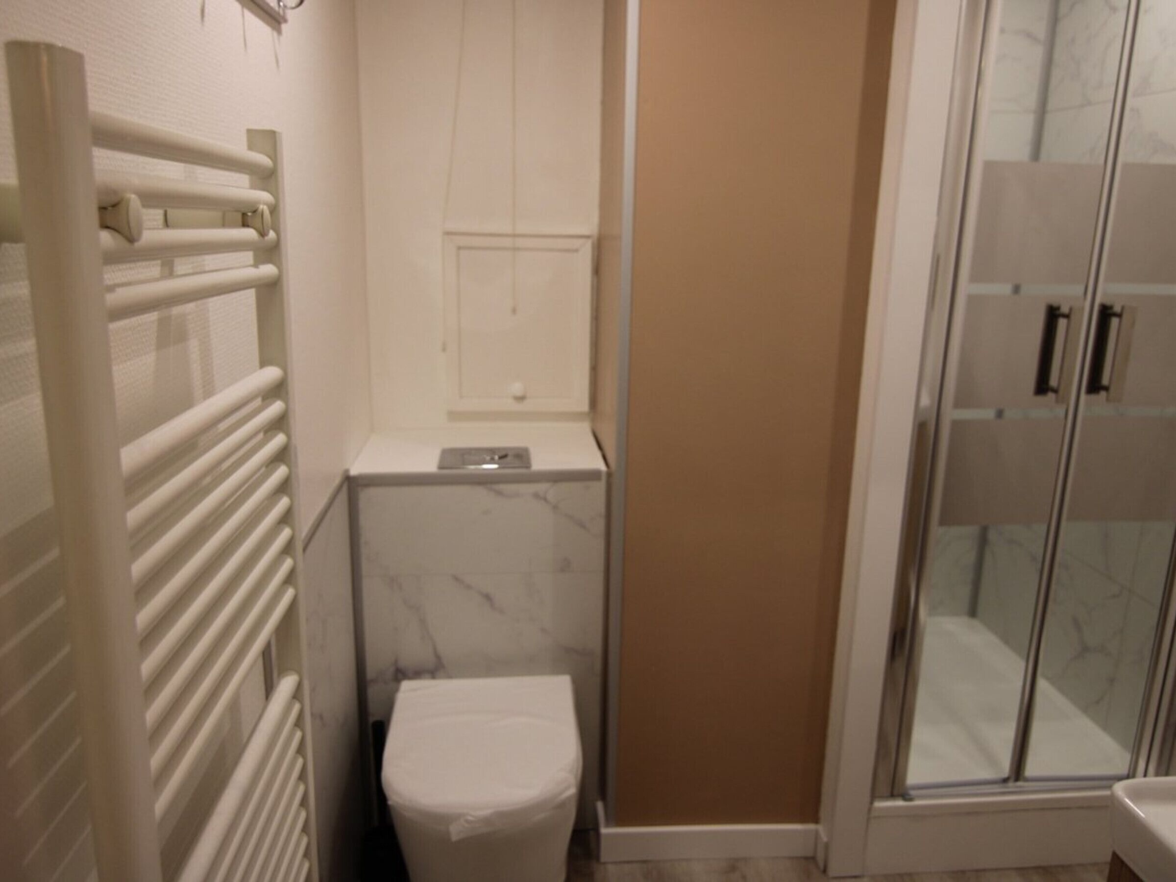 A small bathroom with a toilet, a shower enclosure, and a radiator.