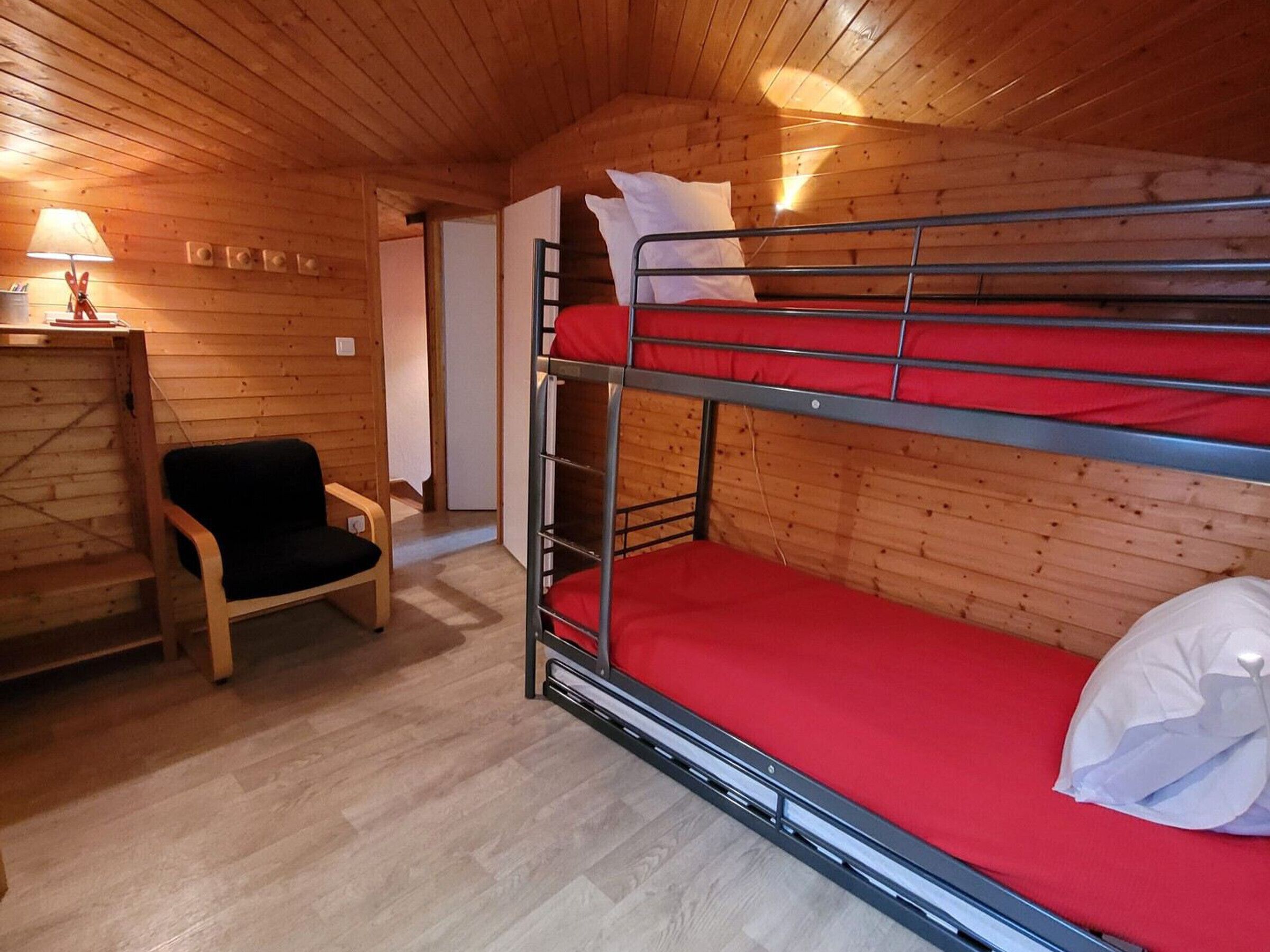 Une chambre avec un lit superposé, des murs en bois et une chaise.