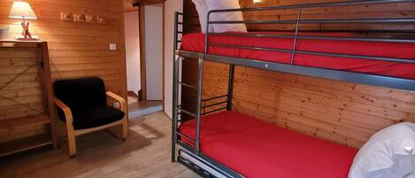 Une chambre avec un lit superposé, des murs en bois et une chaise.
