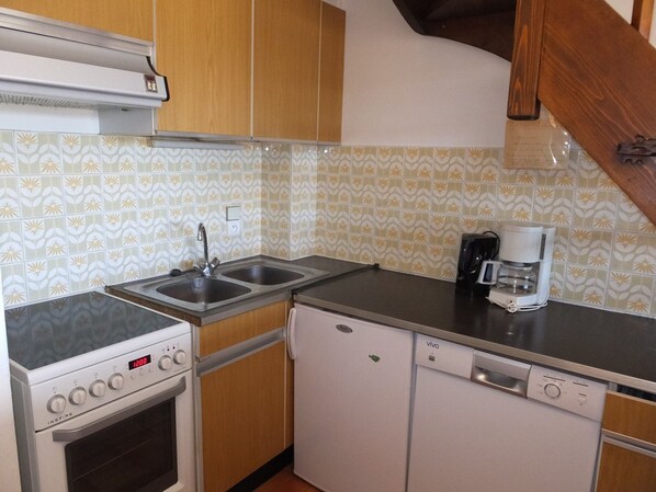 A compact kitchen with a stove, oven, sink, and dishwasher.