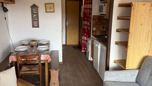 Una cocina compacta con una mesa de comedor preparada para cuatro personas, una lavadora y un microondas.