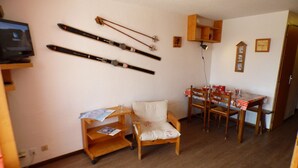 Una sala de estar acogedora con un sofá de madera, una mesa de comedor con sillas y esquíes colgados en la pared.