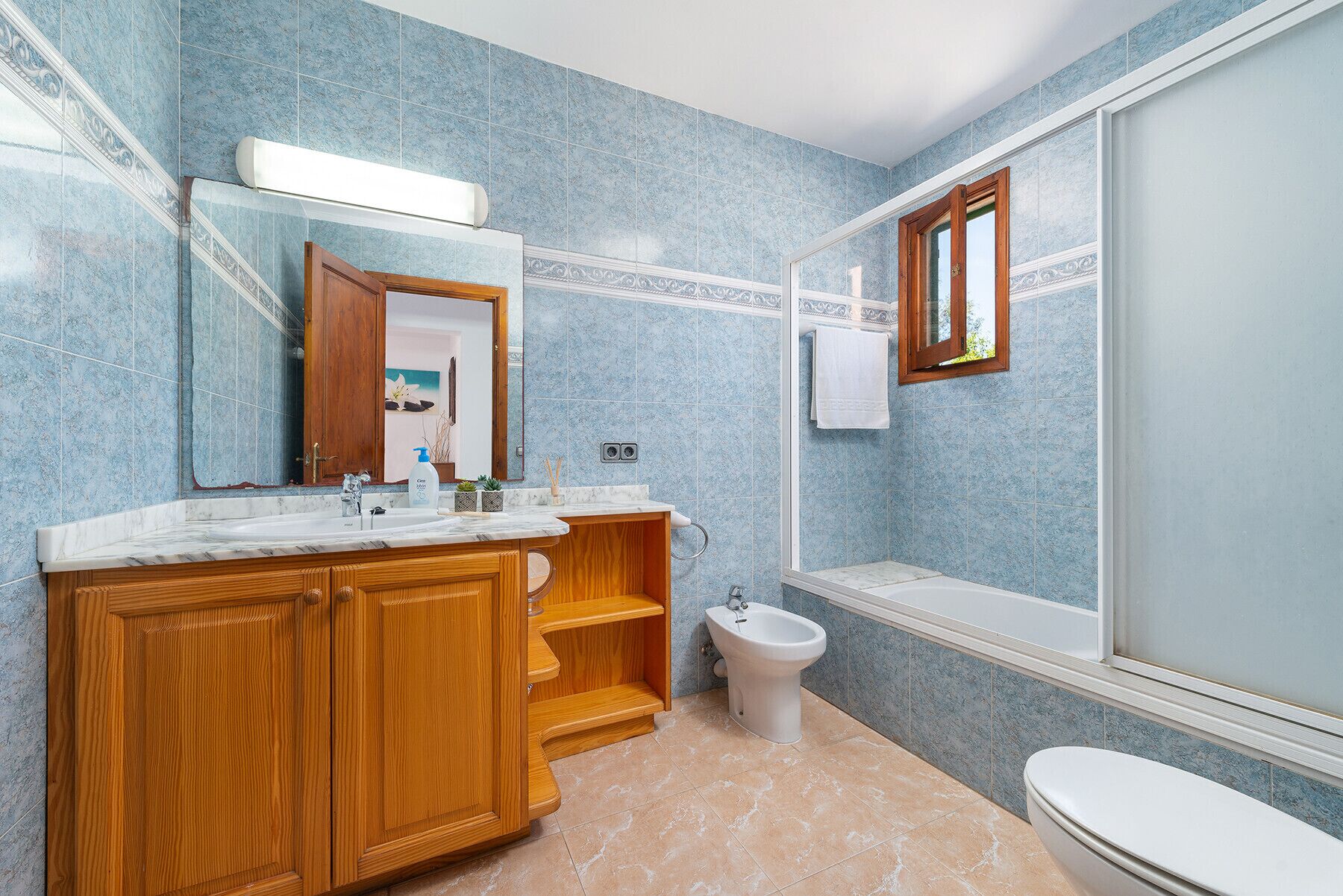 Ein Badezimmer mit einem Holzkosmetikschrank, einem Waschbecken, einem Bidet und einer Toilette.