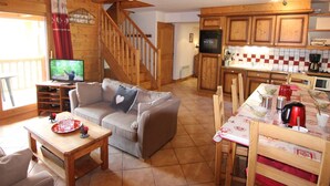 A cozy cabin interior with a living room, dining area, kitchen, and a staircase.