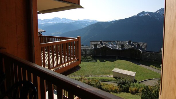 A wooden balcony with a view of a mountain range.