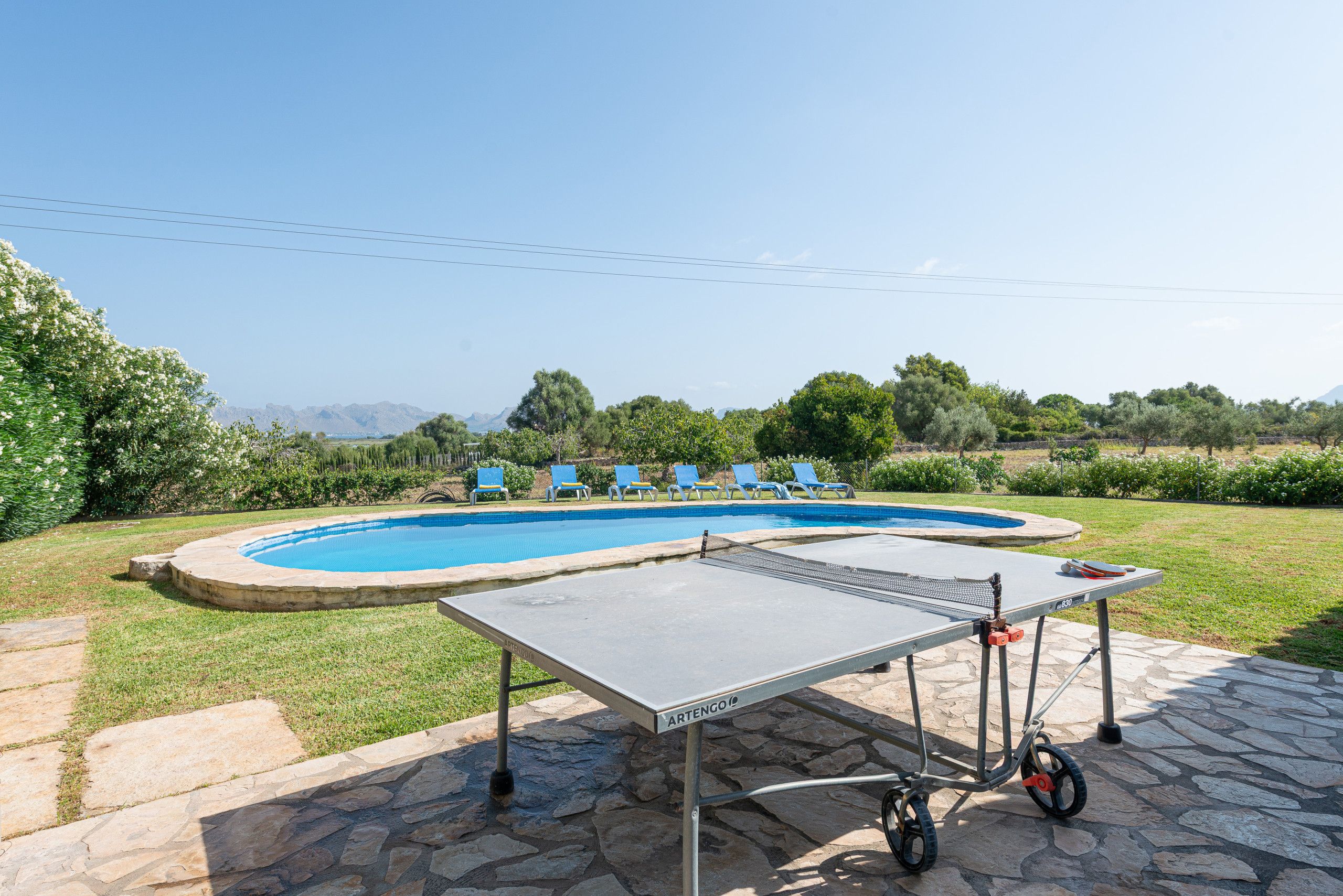 A swimming pool with a table tennis table in the foreground.