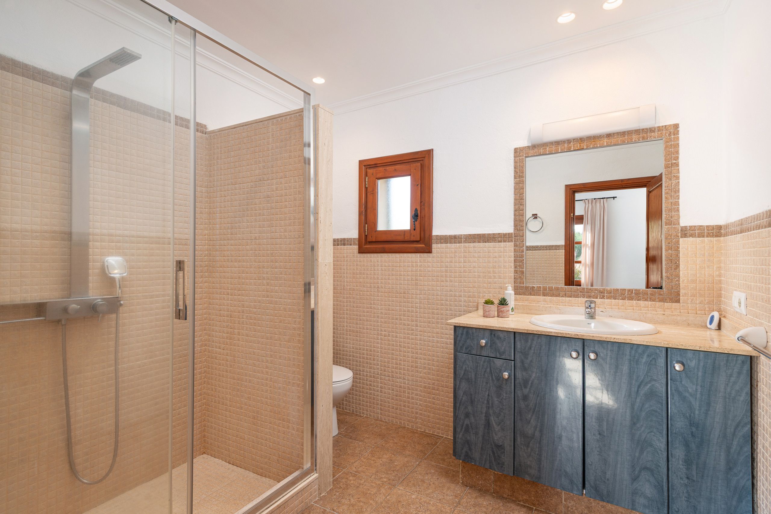 Une salle de bain avec une douche à parois de verre, des toilettes et un lavabo avec un miroir au-dessus.
