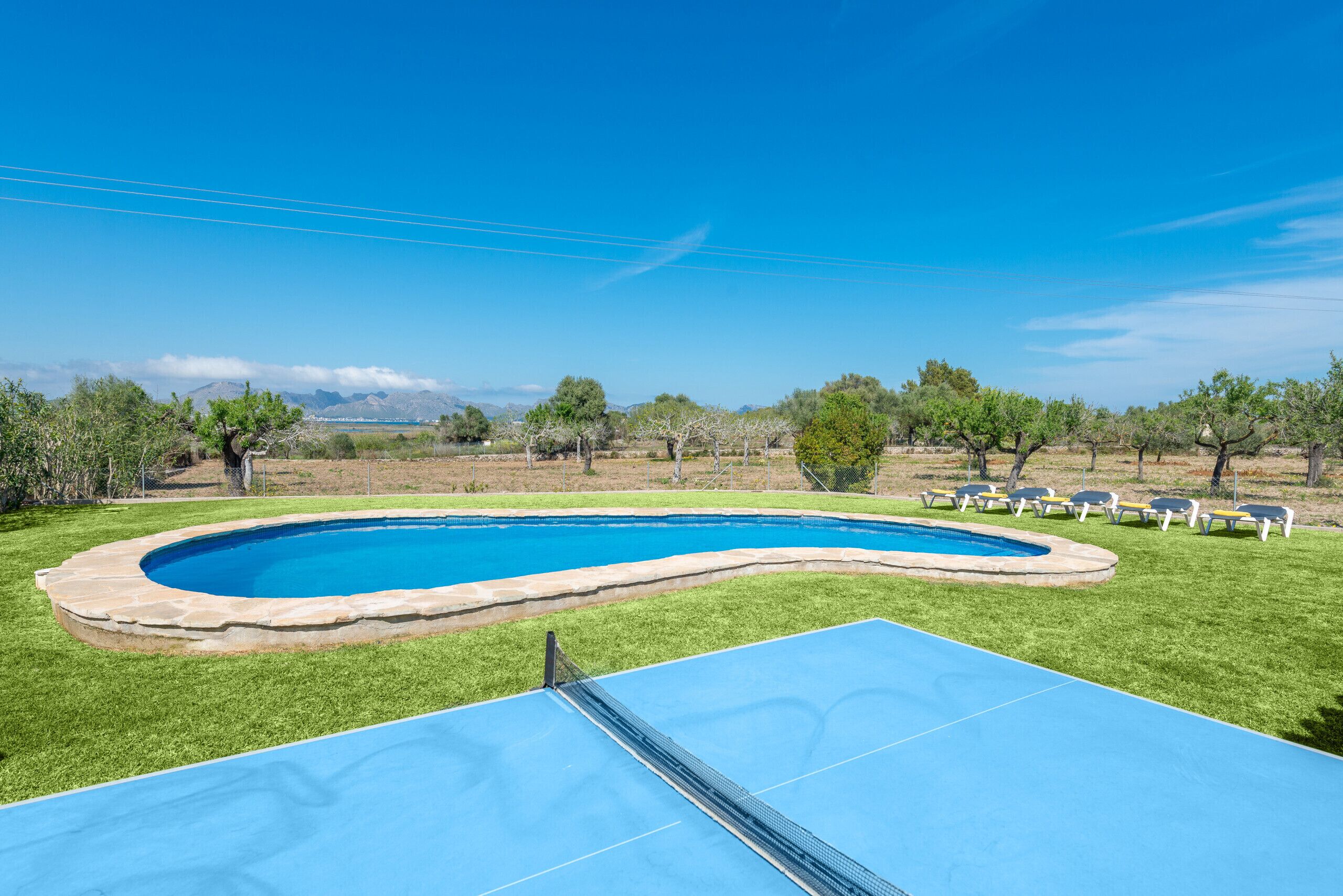 A swimming pool with a blue deck and lounge chairs in the background.