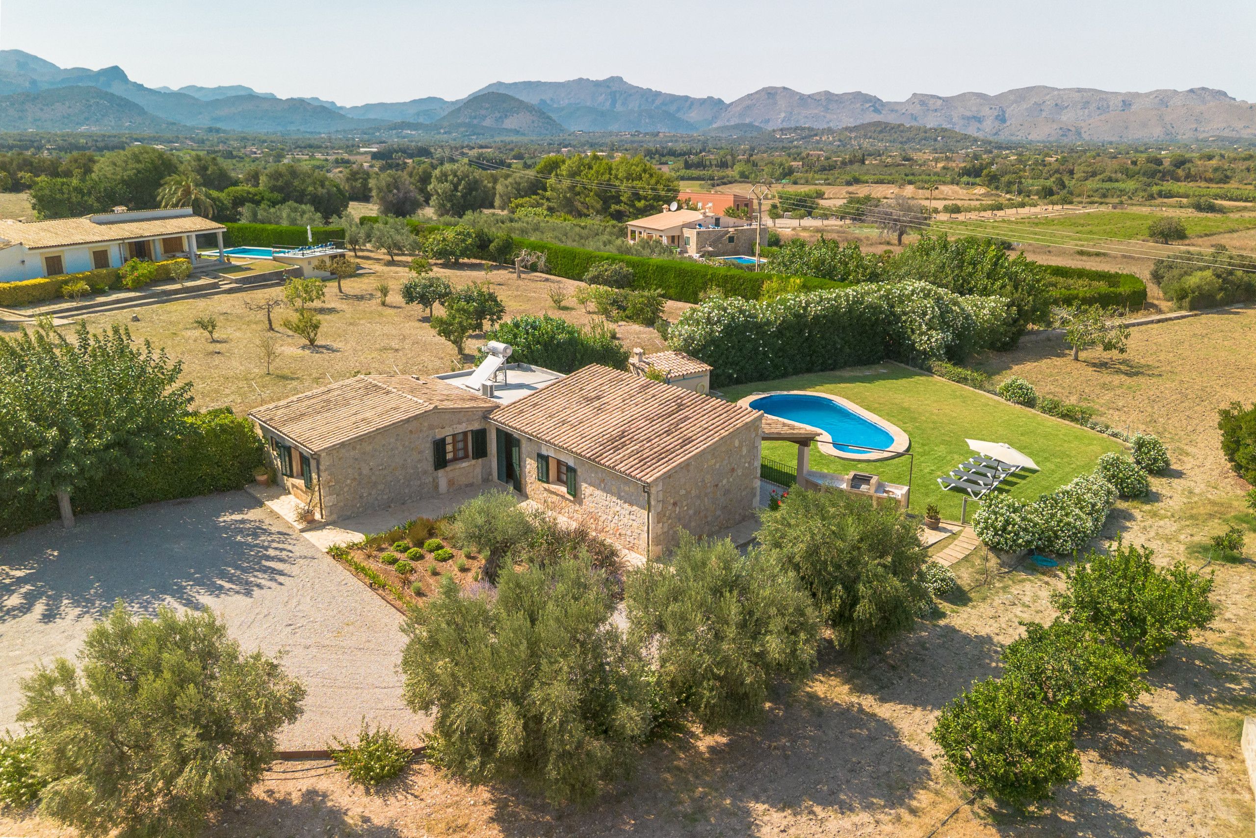 Une villa en pierre dotée d’une piscine, entourée d’une végétation luxuriante et avec des montagnes en toile de fond.