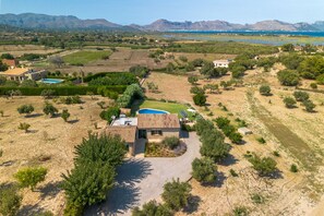 A residential property with a swimming pool, a paved driveway, and a view of the surrounding landscape.